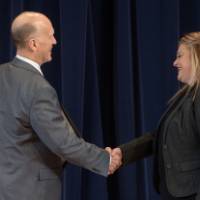 Woman shaking hands with Dean Potteiger on stage as she receives her award